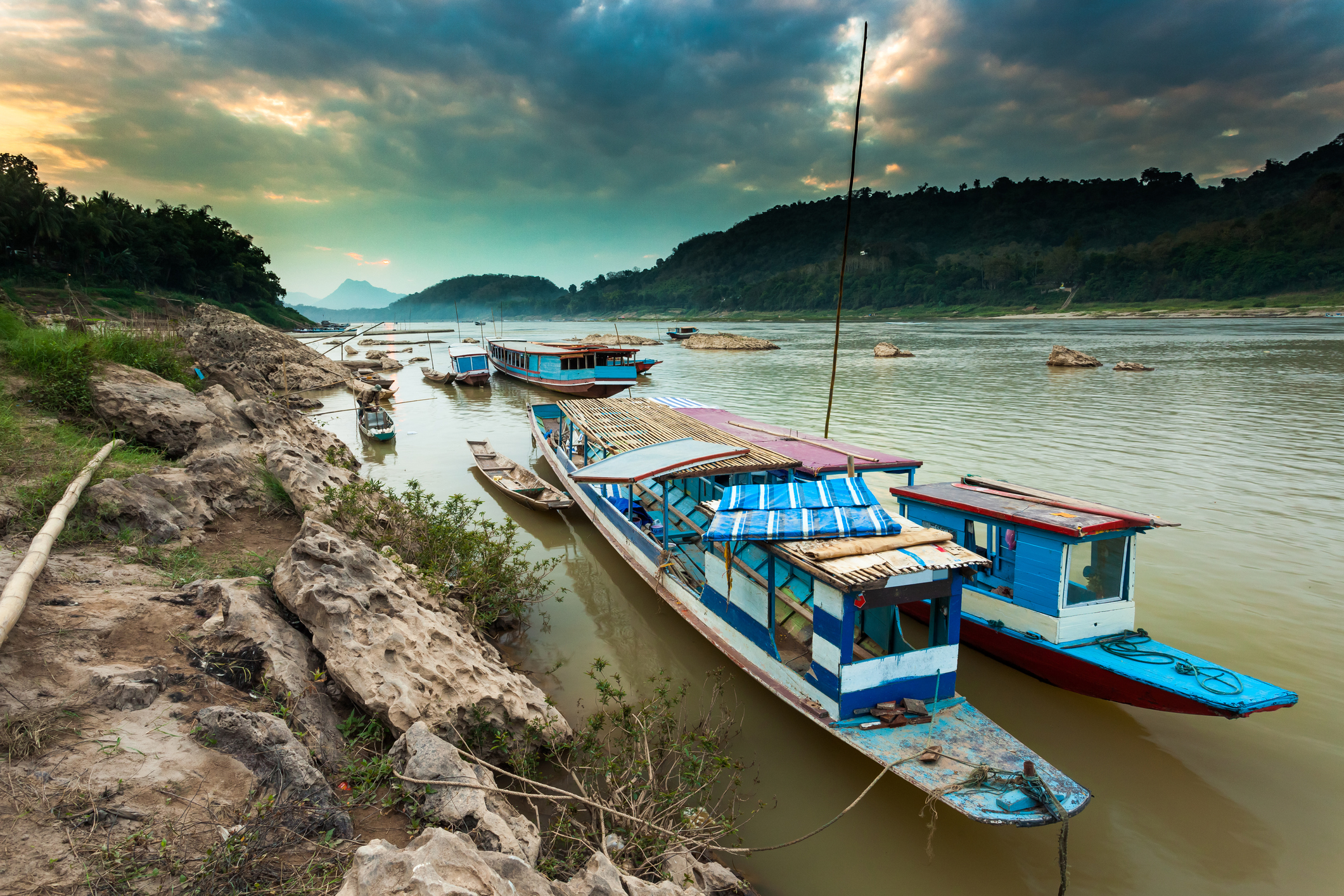 Mekong river, a few small boats by the riverside and Luang Prabang in the background